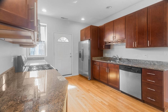 kitchen featuring light hardwood / wood-style flooring, sink, appliances with stainless steel finishes, and dark stone counters