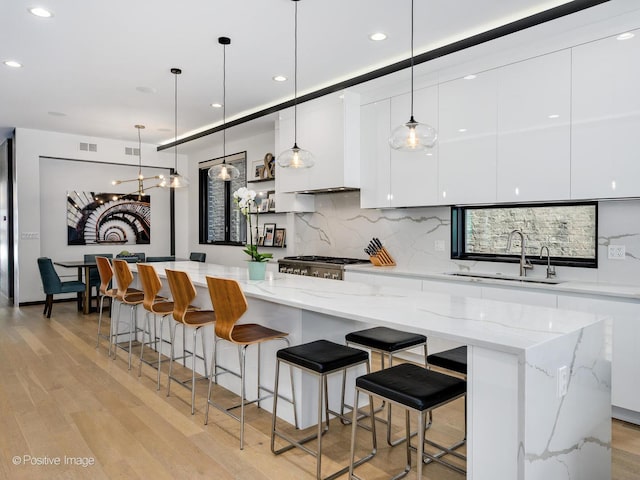 kitchen with white cabinetry, sink, pendant lighting, and a spacious island