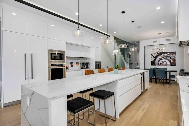 kitchen featuring a large island, pendant lighting, a breakfast bar area, appliances with stainless steel finishes, and white cabinetry