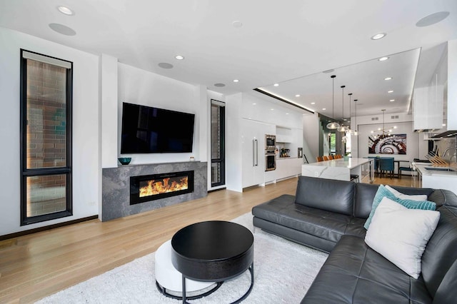 living room featuring sink, a notable chandelier, and light wood-type flooring