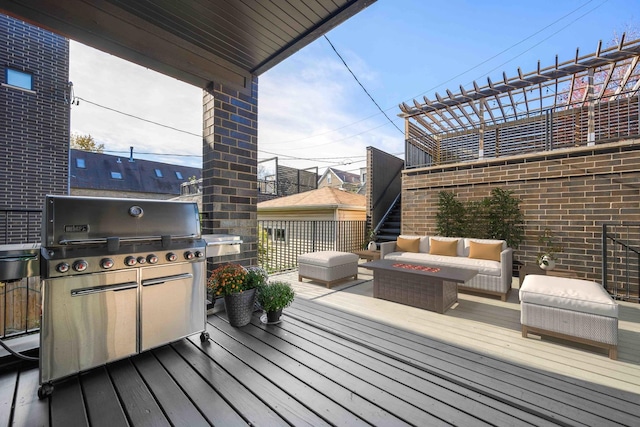 wooden terrace featuring an outdoor kitchen, an outdoor living space with a fire pit, and grilling area