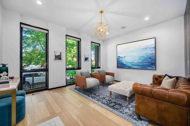 living room with light hardwood / wood-style floors and a notable chandelier