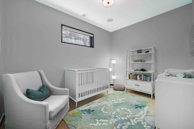 bedroom featuring dark hardwood / wood-style flooring and a crib