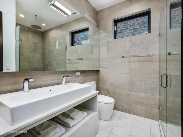 bathroom featuring toilet, sink, tile walls, and a shower with shower door