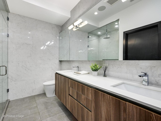 bathroom with a shower with door, vanity, tile walls, and toilet