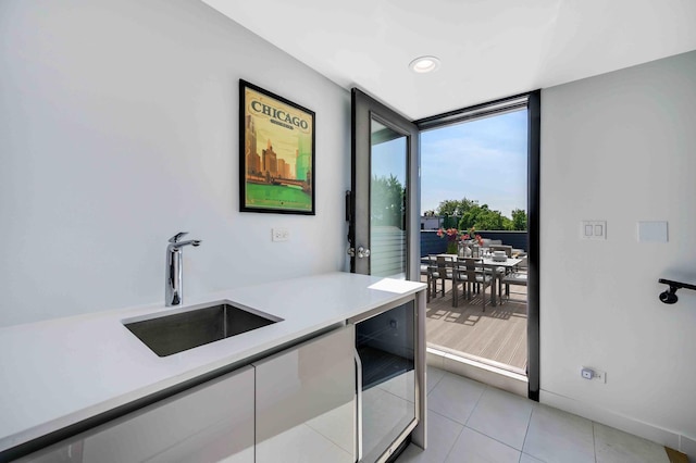 kitchen featuring light tile patterned flooring, expansive windows, beverage cooler, and sink