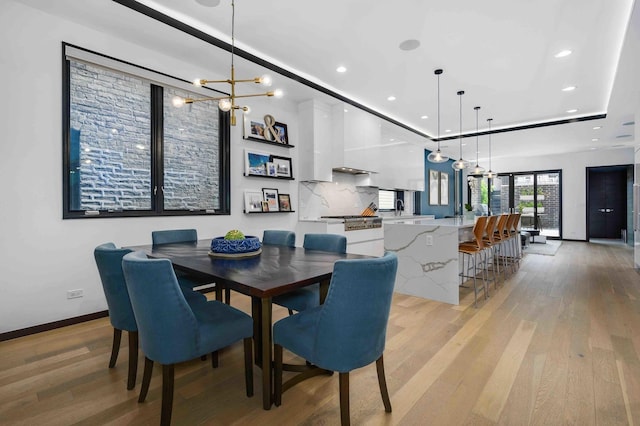 dining space featuring an inviting chandelier, light wood-type flooring, and a tray ceiling