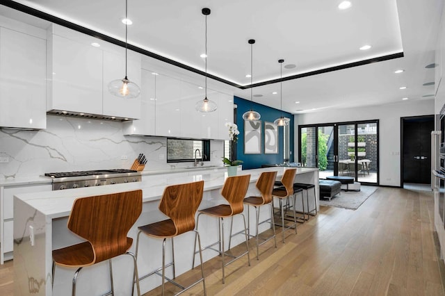 kitchen featuring a spacious island, white cabinetry, a tray ceiling, and decorative light fixtures