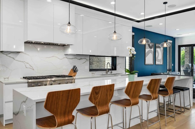 kitchen featuring white cabinetry, a large island, decorative light fixtures, and sink