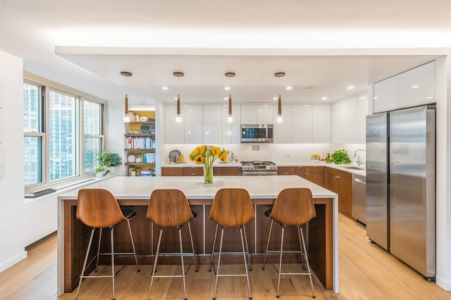 kitchen with a large island, white cabinets, pendant lighting, and appliances with stainless steel finishes