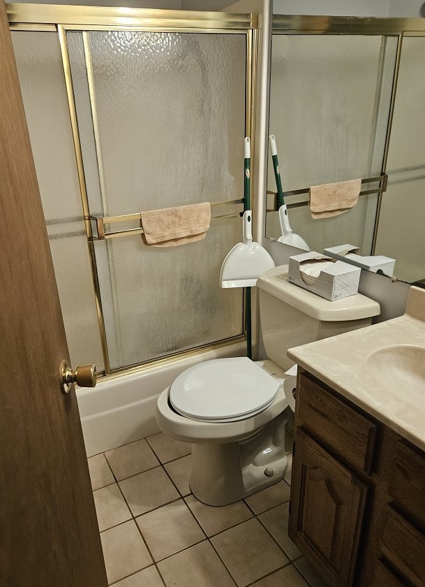 full bathroom with shower / bath combination with glass door, vanity, toilet, and tile patterned flooring