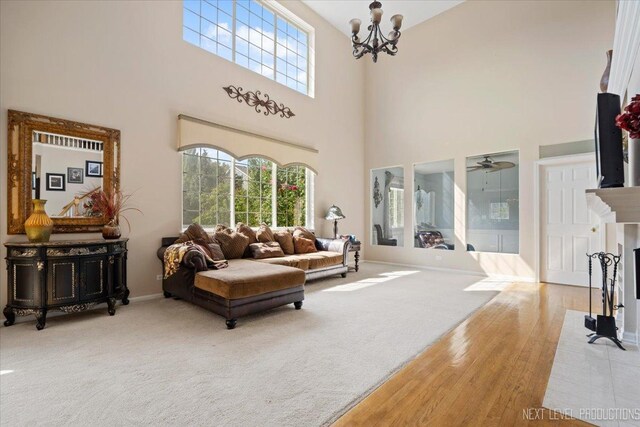 living room with a high ceiling, ceiling fan with notable chandelier, and hardwood / wood-style flooring