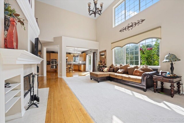 living room featuring a towering ceiling, a chandelier, and light hardwood / wood-style flooring