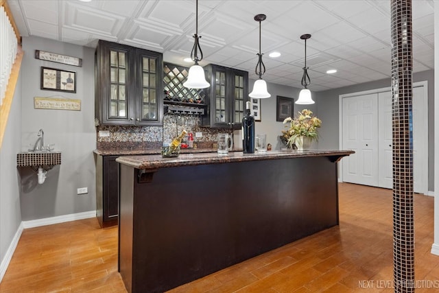 kitchen featuring pendant lighting, light hardwood / wood-style flooring, dark stone counters, and a center island