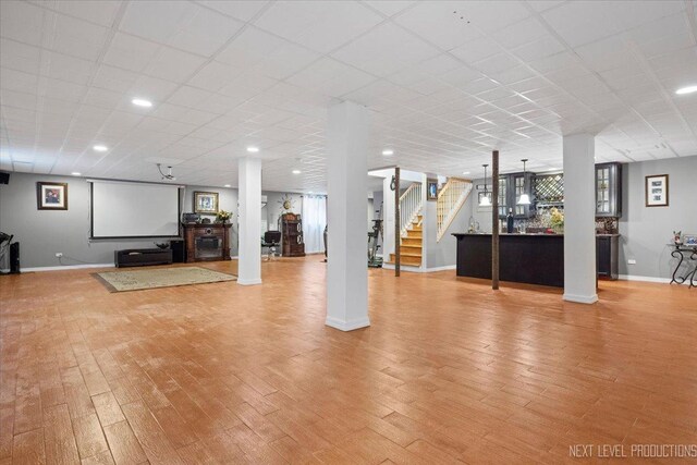 basement featuring a paneled ceiling and light hardwood / wood-style flooring