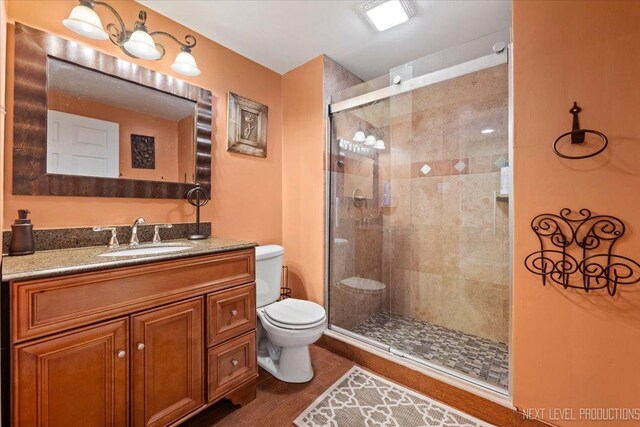 bathroom with vanity, toilet, an enclosed shower, and wood-type flooring