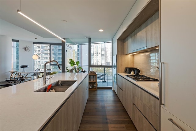 kitchen with sink, hanging light fixtures, stainless steel gas stovetop, dark wood-type flooring, and decorative backsplash