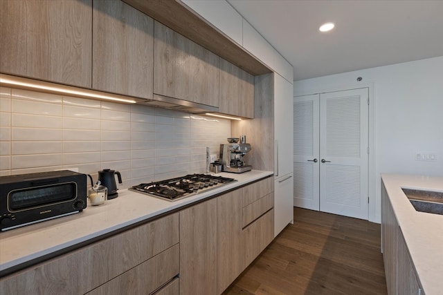 kitchen featuring stainless steel gas cooktop, tasteful backsplash, dark hardwood / wood-style flooring, and light brown cabinets