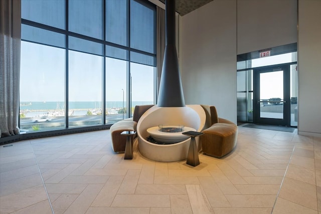 sitting room with a towering ceiling, a healthy amount of sunlight, and a water view