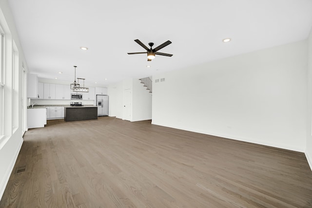 unfurnished living room with ceiling fan and wood-type flooring