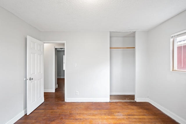 unfurnished bedroom with a textured ceiling, a closet, and dark hardwood / wood-style flooring