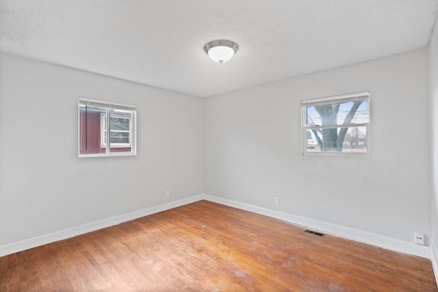 unfurnished room featuring hardwood / wood-style flooring and a textured ceiling