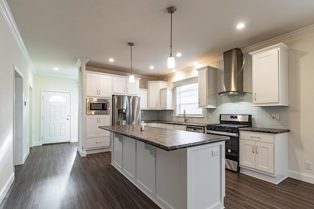 kitchen with a kitchen island, appliances with stainless steel finishes, wall chimney exhaust hood, and white cabinets