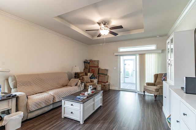 living room featuring dark wood-type flooring, a tray ceiling, ornamental molding, and ceiling fan