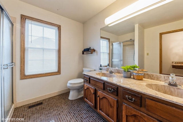 bathroom with a healthy amount of sunlight, walk in shower, toilet, and vanity