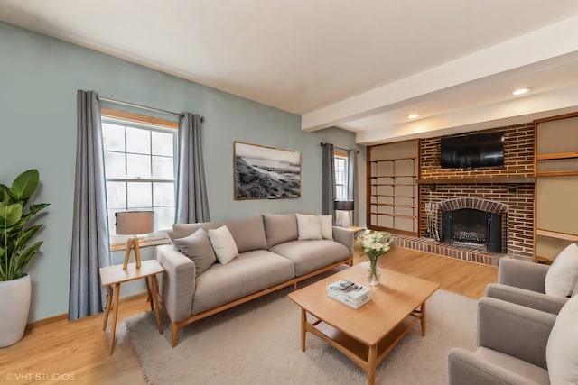 living room with light wood-type flooring, a fireplace, and beam ceiling