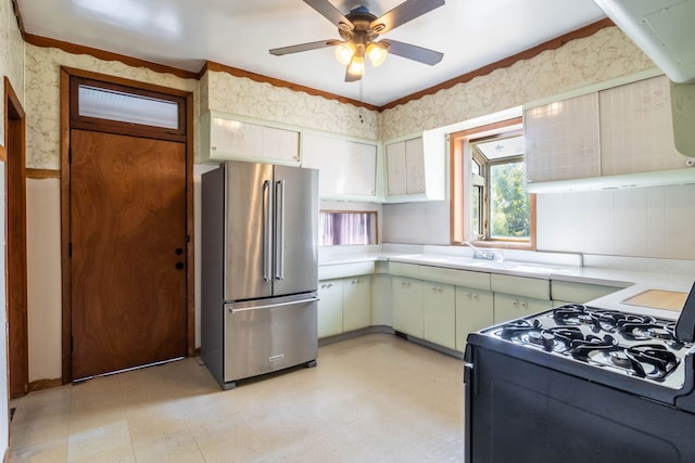 kitchen featuring high end refrigerator, black range, sink, green cabinetry, and ceiling fan