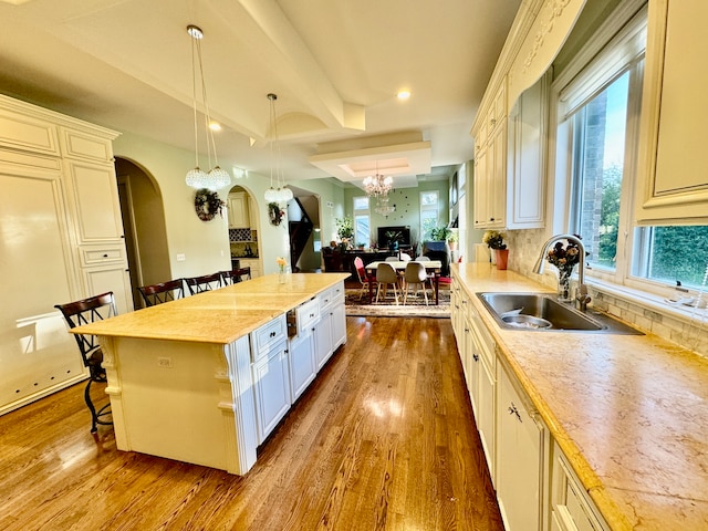 kitchen with pendant lighting, wood-type flooring, a kitchen bar, and a center island