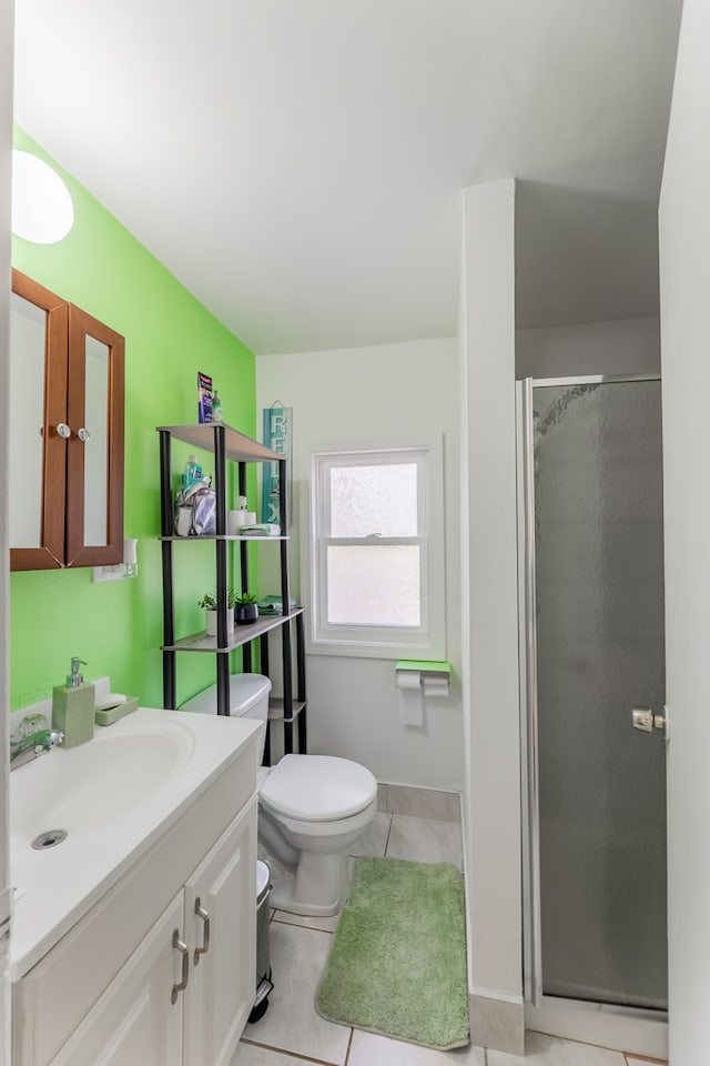 bathroom featuring vanity, toilet, tile patterned floors, and a shower with shower door