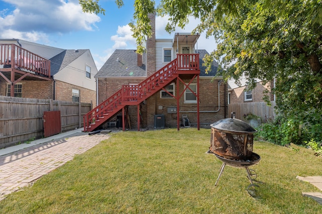 back of house featuring central air condition unit, a yard, an outdoor fire pit, and a deck