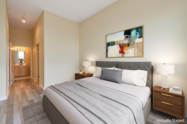 bedroom with ensuite bath and hardwood / wood-style flooring