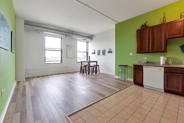 kitchen with light stone countertops, light wood-type flooring, and dishwasher