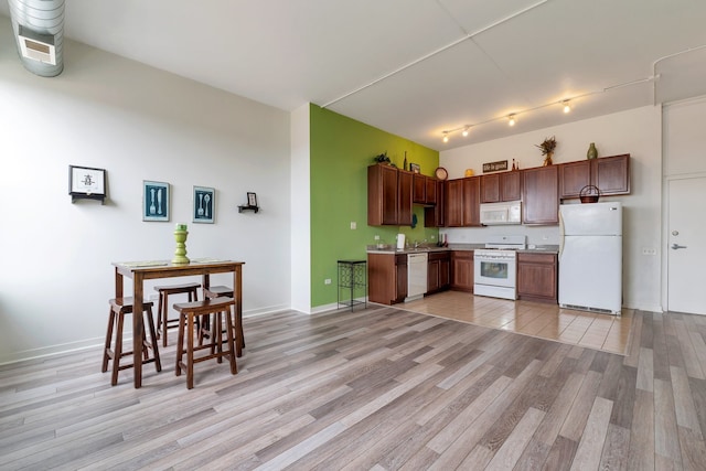 kitchen featuring light hardwood / wood-style flooring, white appliances, and track lighting