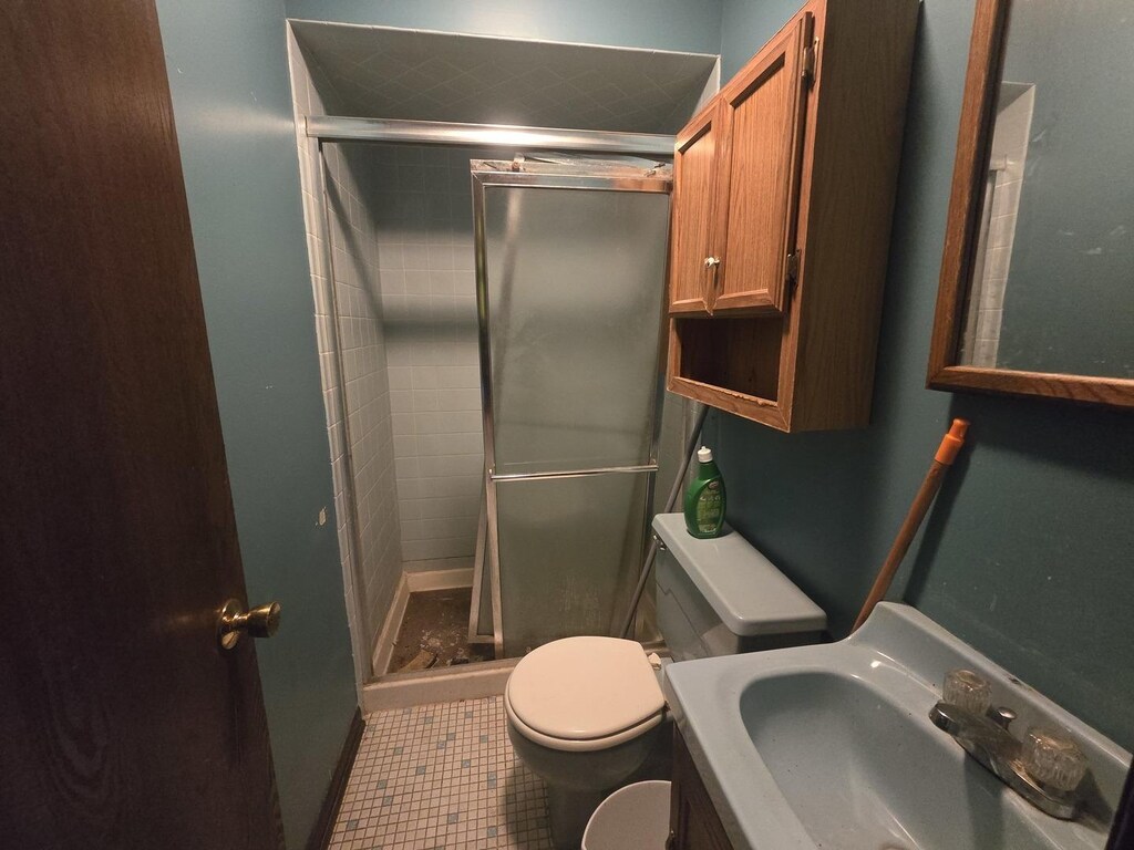 bathroom with an enclosed shower, tile patterned flooring, toilet, and vanity