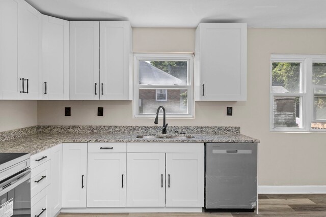 kitchen with white cabinetry, dishwasher, light stone counters, sink, and hardwood / wood-style flooring