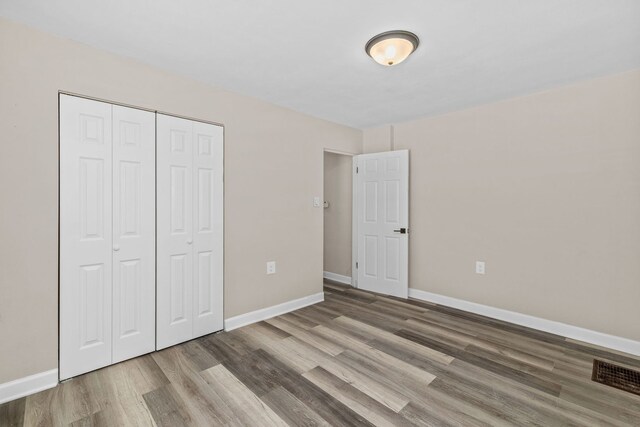 unfurnished bedroom featuring a closet and hardwood / wood-style flooring