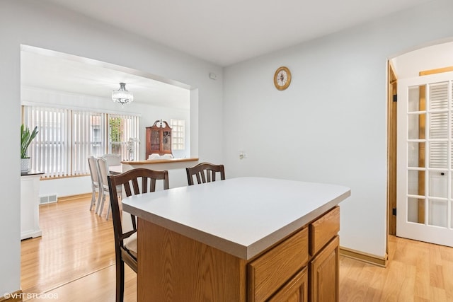 kitchen featuring light wood-style floors, a kitchen island, a chandelier, and brown cabinetry