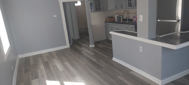 kitchen featuring stainless steel refrigerator, sink, dark wood-type flooring, and gray cabinets