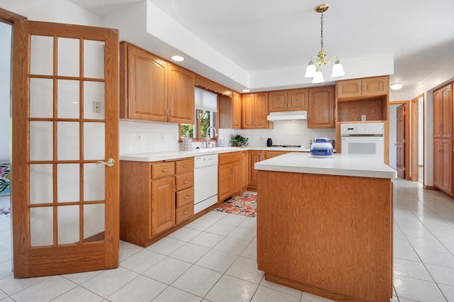 kitchen with a chandelier, a center island, white appliances, backsplash, and decorative light fixtures