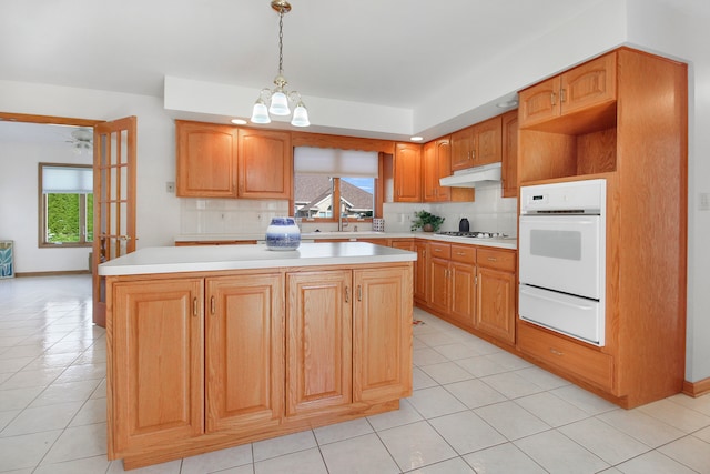 kitchen with decorative light fixtures, a chandelier, oven, a center island, and decorative backsplash