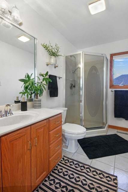 bathroom with vanity, toilet, tile patterned floors, and a shower with shower door