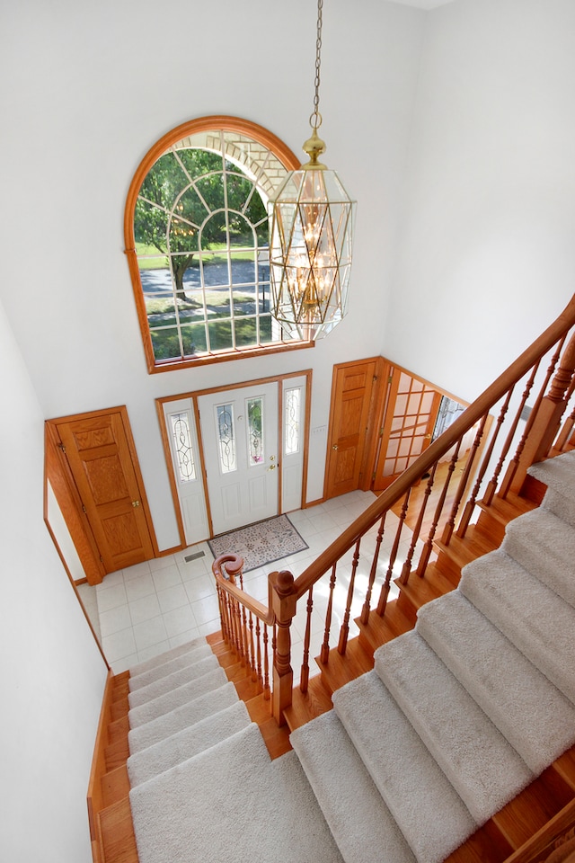 entrance foyer featuring a notable chandelier, light wood-type flooring, and a high ceiling