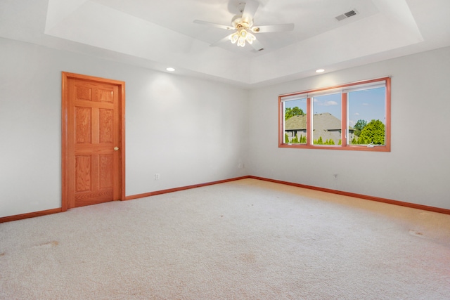 spare room featuring carpet, a tray ceiling, and ceiling fan