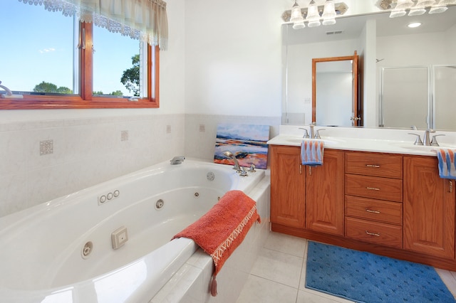 bathroom with tiled tub, vanity, and tile patterned flooring