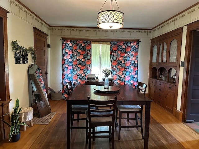 dining space with ornamental molding and dark hardwood / wood-style flooring