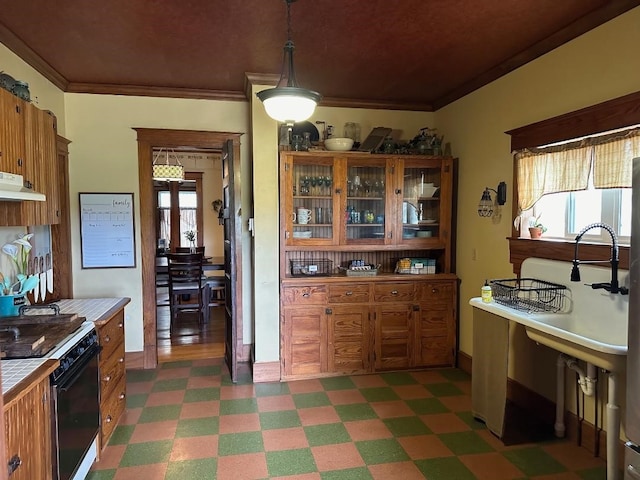 kitchen featuring pendant lighting, ornamental molding, tile counters, and a wealth of natural light